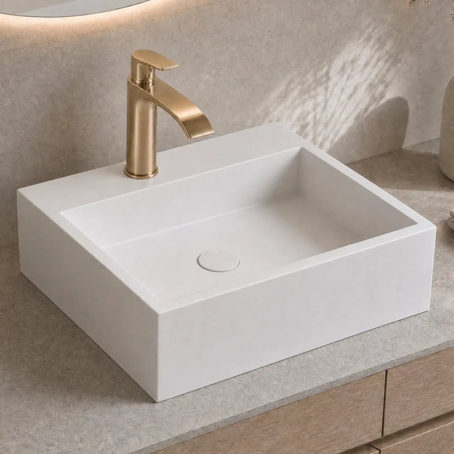 White rectangular sink with gold faucet on a beige countertop