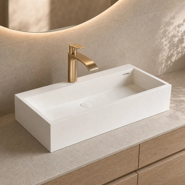 White rectangular sink with gold faucet on a beige countertop