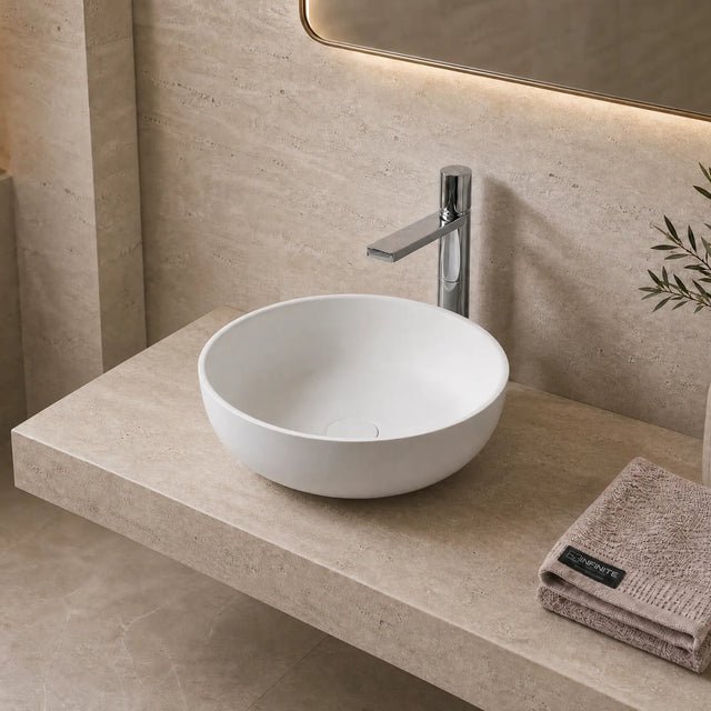 Bathroom with a white solid surfaces sink on a stone countertop, illuminated by warm lighting.