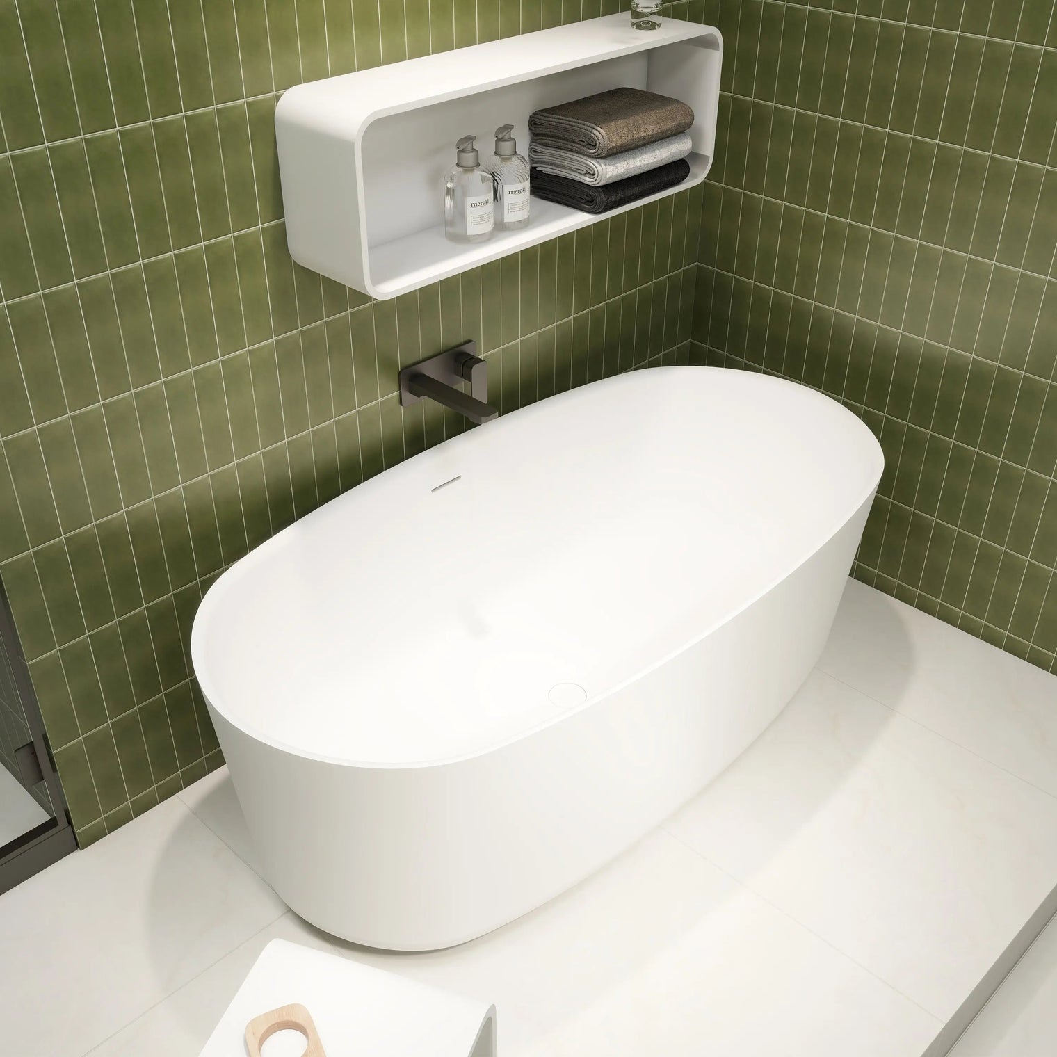 Modern white freestanding bathtub in a bathroom with green tiled walls.