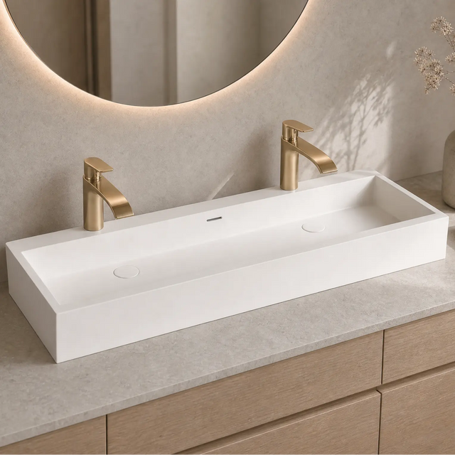 Bathroom vanity with white rectangular sink, gold faucets, and decorative elements.