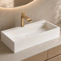 White rectangular sink with gold faucet on a beige countertop