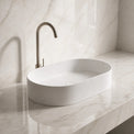 White Solid Surfaces oval sink on a marble countertop with a matching wall.