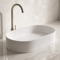 White Solid Surfaces oval sink on a marble countertop with a matching wall.