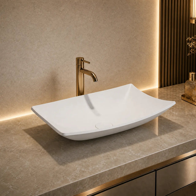 White rectangular Solid Surfaces sink on a gray countertop with a gold faucet in a modern bathroom setting.