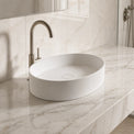 White Solid Surfaces oval sink on a marble countertop with a silver faucet.