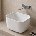 Modern bathroom with a white freestanding Solid Surfaces sink, faucet, and decorative elements.