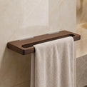 Towel hanging on a wooden towel rack in a bathroom with marble walls and a sink.